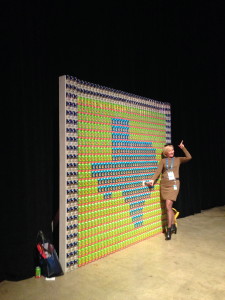 A woman gets her picture taken in front of a beer can creation at DellWorld 